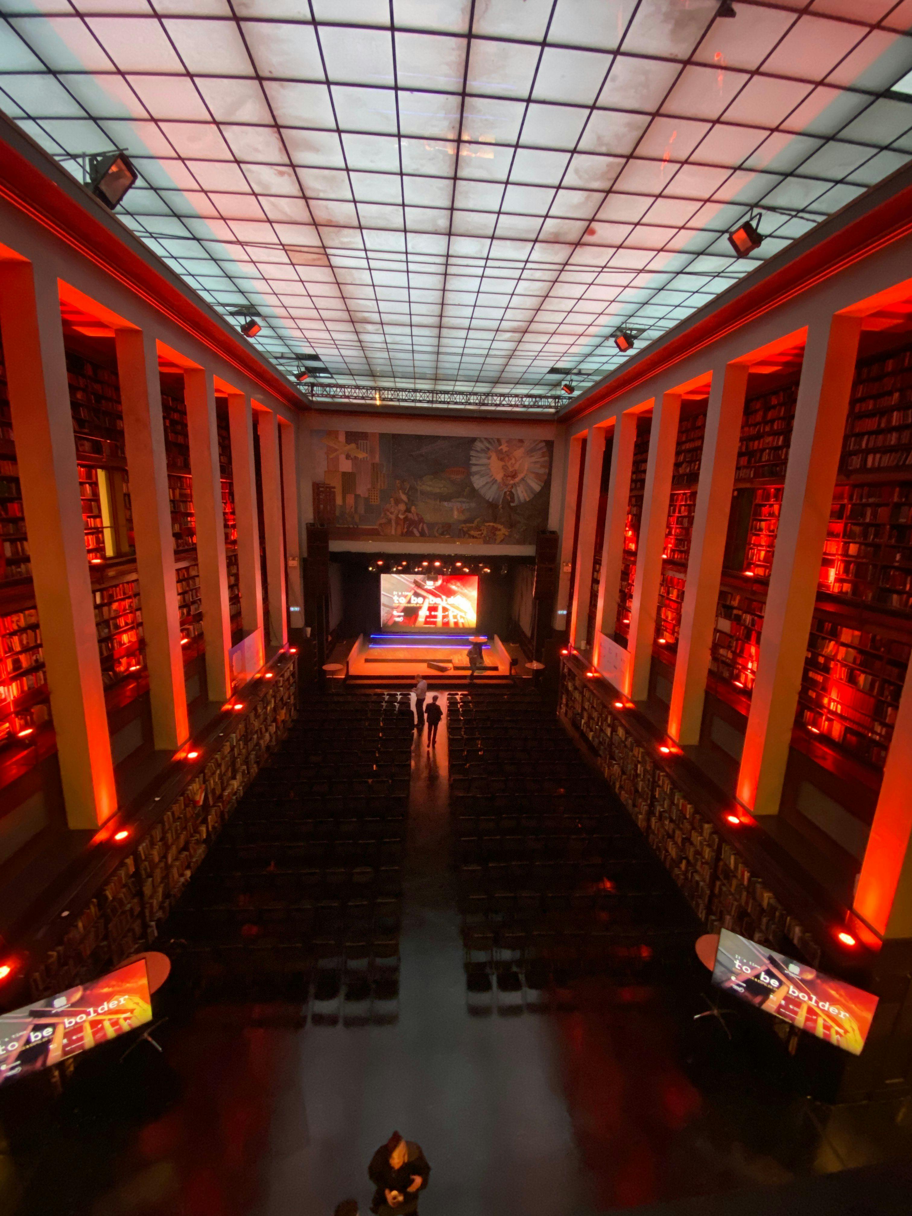 Stor ærverdig sal med rødt lys og scene og LED skjerm i den ene endren. Foto. 